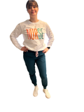 A person standing, wearing a white long sleeve t-shirt with the word 'NURSE' printed on the front, and blue pants.